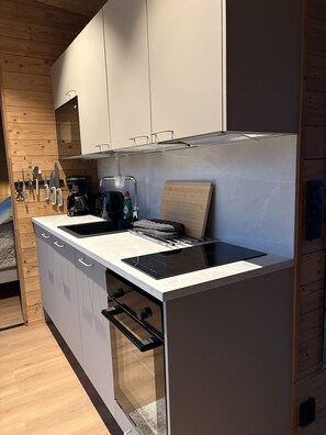 A modern kitchen with a built-in stove, a coffee maker, and a knife block.