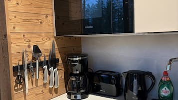Une cuisine équipée d’une machine à café, d’un grille-pain, d’une bouilloire et d’un réfrigérateur Siemens.