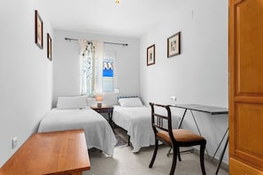 A bedroom with two beds, a desk, a chair, and a window with curtains. - Ocean Views on the Sabinillas Boardwalk (San Luis de Sabinillas)
