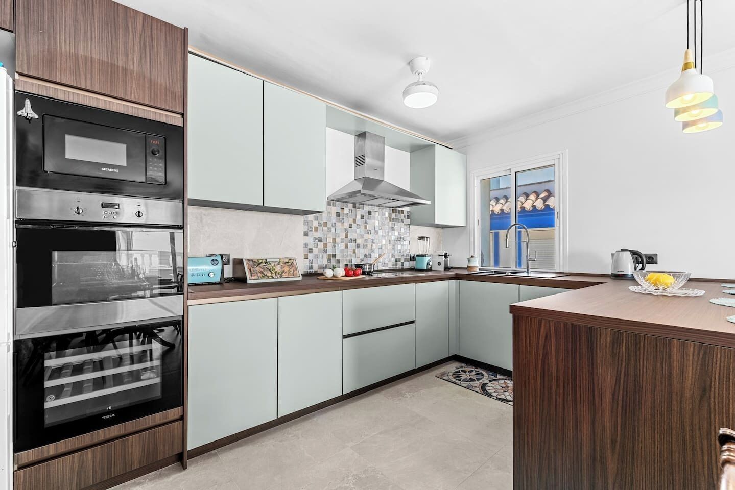 A modern kitchen with a built-in oven, microwave, and a large island with a sink.