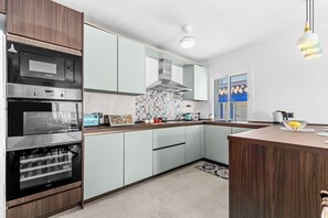 A modern kitchen with a built-in oven, microwave, and a large island with a sink. - Ocean Views on the Sabinillas Boardwalk (San Luis de Sabinillas)