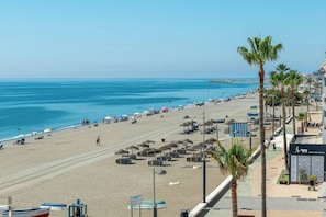 A beach with umbrellas, lounge chairs, and a clear view of the ocean. - Ocean Views on the Sabinillas Boardwalk (San Luis de Sabinillas)