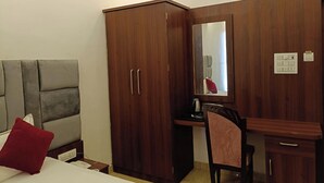 A bedroom with a bed, a wardrobe, a desk, and a chair.