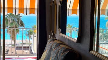 Habitación con vista al mar a través de amplios ventanales, un sofá y un espejo en la pared.