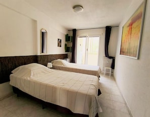 A hotel room with two beds, a window, a radiator, and a chair. - Beautiful 2-bedroom apartment with seaview in gorgeous Nice - Azure Paradise (Nice)