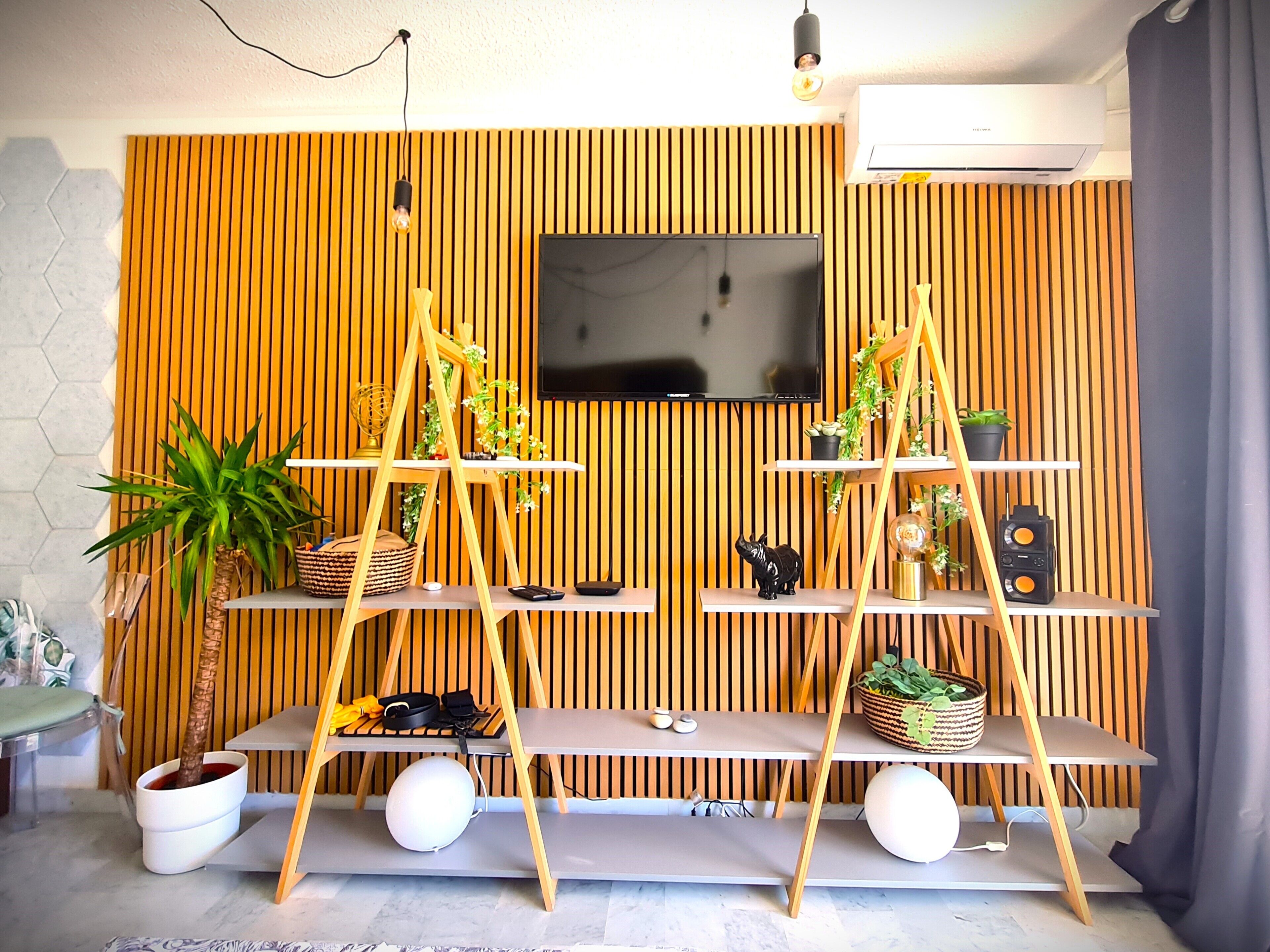 Una sala de estar moderna con un televisor instalado en una pared de madera, un sofá y una mesa de centro.