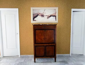 Un mueble de madera con encimera de mármol frente a una pared amarilla, flanqueado por puertas blancas.