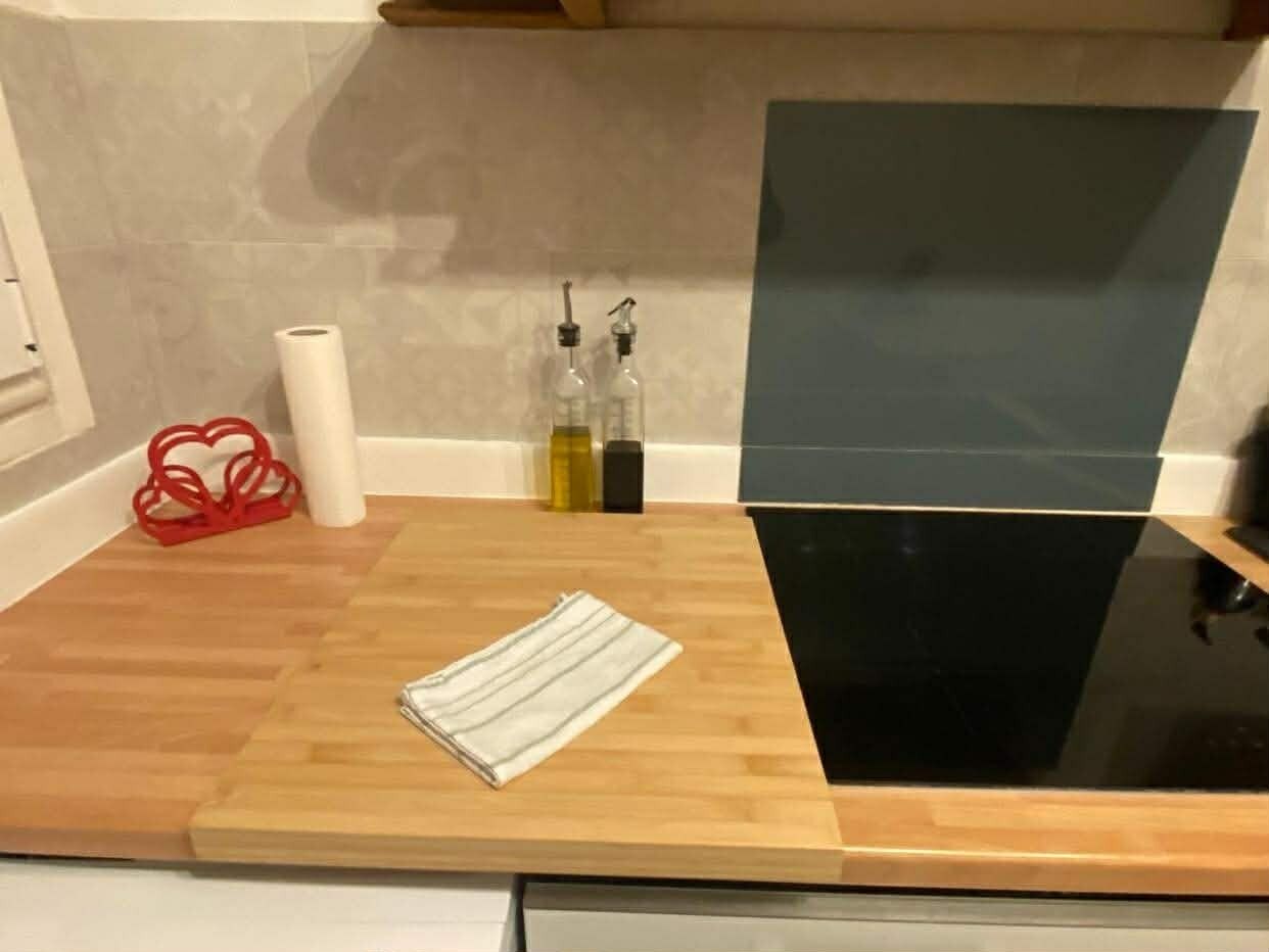 Una encimera de cocina con una tabla de cortar de madera, un paño a rayas y dos botellas de aceite de oliva.
