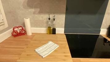 Una encimera de cocina con una tabla de cortar de madera, un paño a rayas y dos botellas de aceite de oliva.