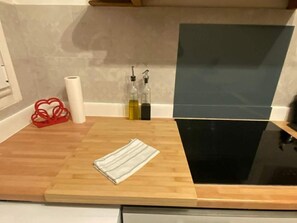 Una encimera de cocina con una tabla de cortar de madera, un paño a rayas y dos botellas de aceite de oliva.