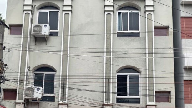 Un edificio con un letrero que dice 'SVR ELITE ROOMS' y un local comercial en la planta baja.