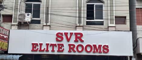 A building with a sign for 'SVR ELITE ROOMS' and a storefront below.