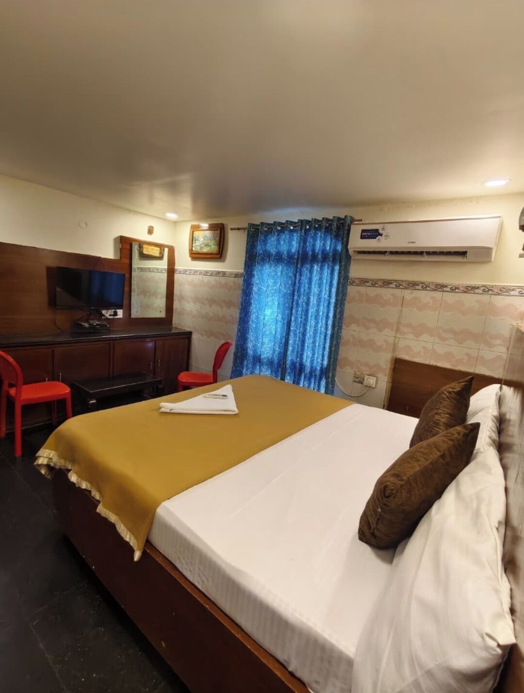 Une chambre d’hôtel équipée d’un lit, d’un bureau, d’une télévision et d’un appareil de climatisation.