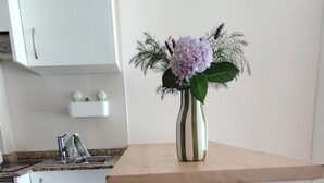 A kitchen with a wooden shelf holding a vase with flowers, a tea box, and jars. - Apartment '2 Bedroom  On The Beach' with Sea View and Wi-Fi (Moaña)