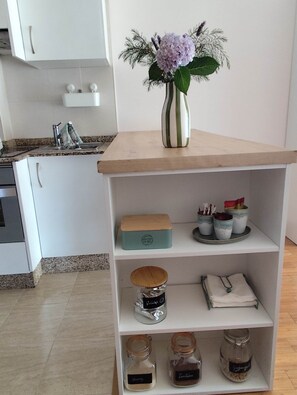 Eine Küche mit einem Holzboden, der eine Vase mit Blumen, eine Tee-Box und Gläser beherbergt.