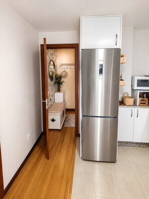 Eine Küche mit einem Edelstahlkühlschrank, weißen Schränken, einer Mikrowelle und einem Holzboden.