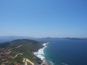 Un paysage côtier avec une route sinueuse, des collines verdoyantes et une vue sur l’océan.