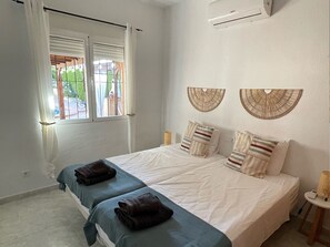 A bedroom with two beds, a window with curtains, and wall-mounted wall art. - Beautiful villa with a pool, ideal for 1 or 2 families (Busot)