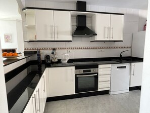 A modern kitchen with white cabinets, a black countertop, and a built-in oven. - Beautiful villa with a pool, ideal for 1 or 2 families (Busot)