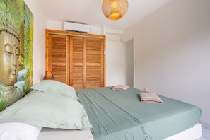Ein Schlafzimmer mit einem Bett, einem Holzschrank, einer Wand-Klimaanlage und einer Pendelleuchte.