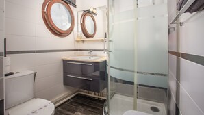 Ein Badezimmer mit Toilette, einem Waschbecken mit Spiegel darüber und einer Duschkabine.