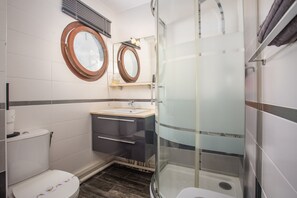 Ein Badezimmer mit Toilette, einem Waschbecken mit Spiegel darüber und einer Duschkabine.