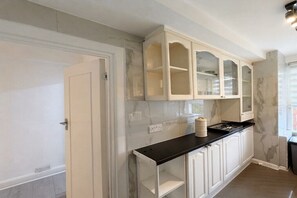 A kitchen with white cabinetry, a black countertop, and a marble backsplash. - Mayfair Beautiful Family Apartment (London)