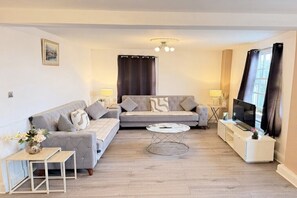 A living room with a sofa, a coffee table, a TV, and a lamp. - Mayfair Beautiful Family Apartment (London)