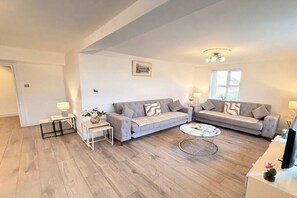 A modern living room with two grey sofas, a coffee table, and a TV. - Mayfair Beautiful Family Apartment (London)