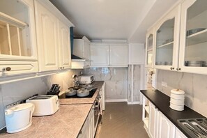 A modern kitchen with white cabinets, a black countertop, and a built-in oven. - Mayfair Beautiful Family Apartment (London)