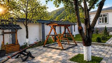 A patio area with a swing set, a small wooden structure, and a potted plant.