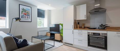 Una cocina moderna con armarios blancos, un horno y una zona de comedor con una mesa y sillas.