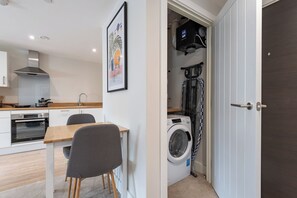 A compact kitchen with a stove, oven, and a dining area with a table and chairs. - 1Bedroom Apartment in Hull City Centre (Kingston upon Hull)