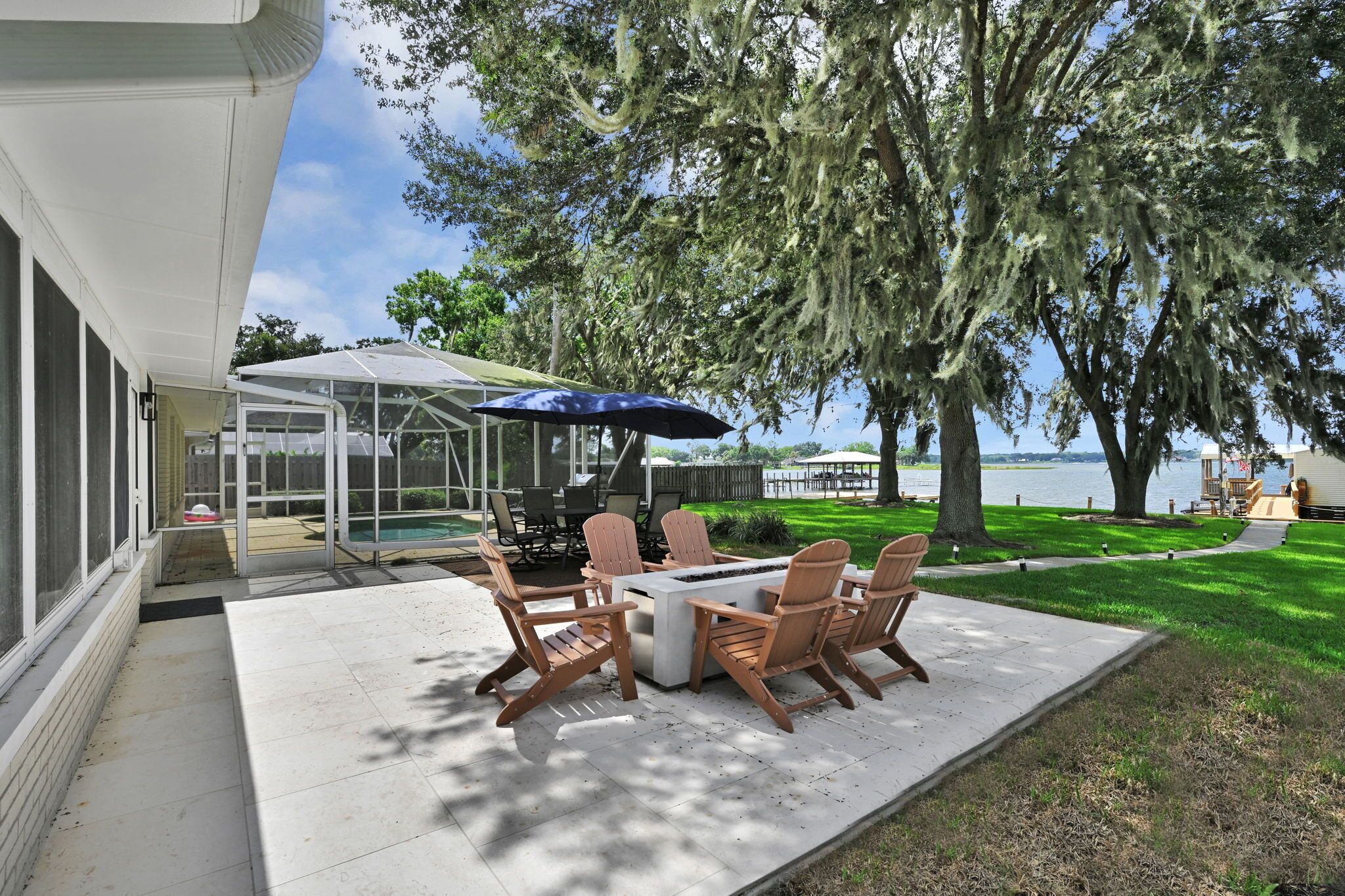 A patio with a table and chairs, a covered area, and a view of a lake.