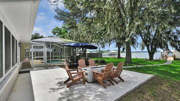 A patio with a table and chairs, a covered area, and a view of a lake.