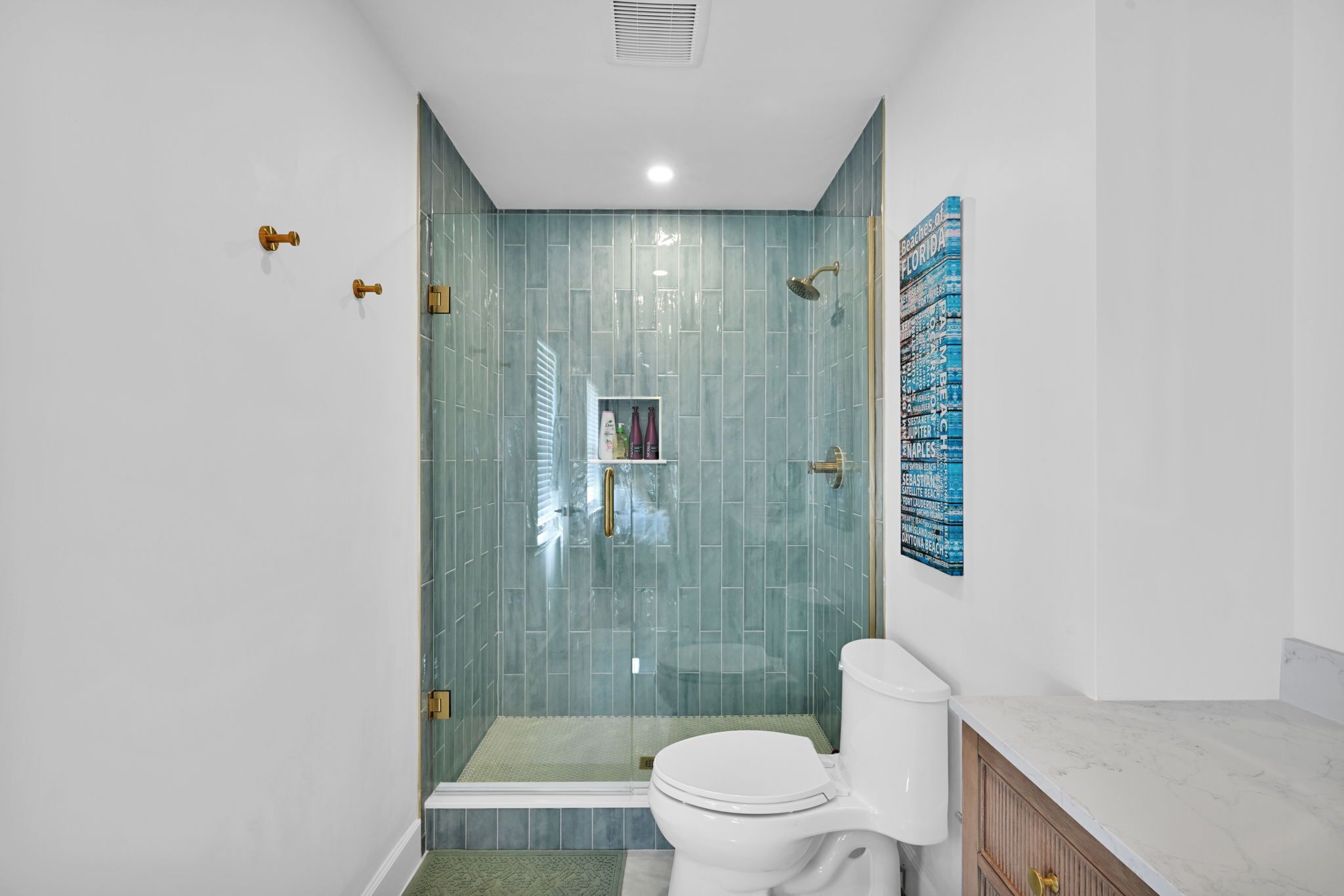A modern bathroom with a glass-enclosed shower, a toilet, and a marble countertop.
