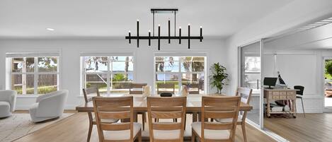 En moderne spisestue med et træbord og stole, store vinduer og en loftlampe.