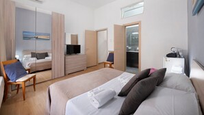 A hotel room with a bed, a TV, a desk, a chair, a wardrobe, and a bathroom. - Home Joséphine - Caserta - Quadruple Room with Private Bathroom (Caserta)