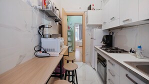 A compact kitchen with a coffee maker, a kettle, and a stove. There is a small dining area with stools. - Home Joséphine - Caserta - Quadruple Room with Private Bathroom (Caserta)