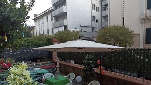 Ein Außenbereich mit Tischen, Stühlen und einem großen Sonnenschirm, umgeben von einem dekorativen Zaun.