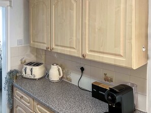 Eine Küche mit einer Granitabdeckung, einer Kaffeemaschine, einem Toaster und einer schwarzen Espressomaschine.