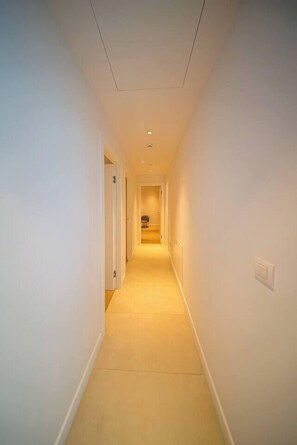 A narrow, well-lit hallway with a carpeted floor and white walls. - Napa Horizon | Sea Front | Marina Tower 1702 (Ayia Napa)