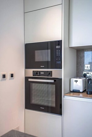A kitchen with a built-in microwave and oven, a toaster, and a marble countertop. - Napa Horizon | Sea Front | Marina Tower 1702 (Ayia Napa)