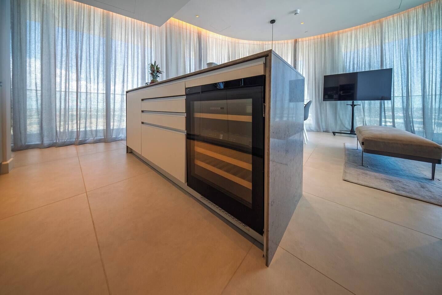 A modern living room with a built-in oven, a flat-screen TV, and a bench.