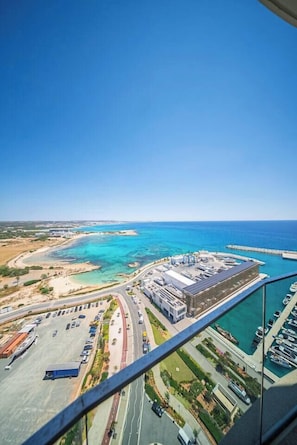A coastal cityscape with a marina, roads, and buildings. - Napa Horizon | Sea Front | Marina Tower 1702 (Ayia Napa)