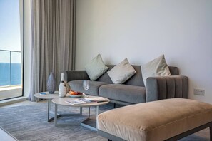 A modern living room with a grey sofa, a small round table, and a beige ottoman. - Napa Horizon | Sea Front | Marina Tower 1702 (Ayia Napa)