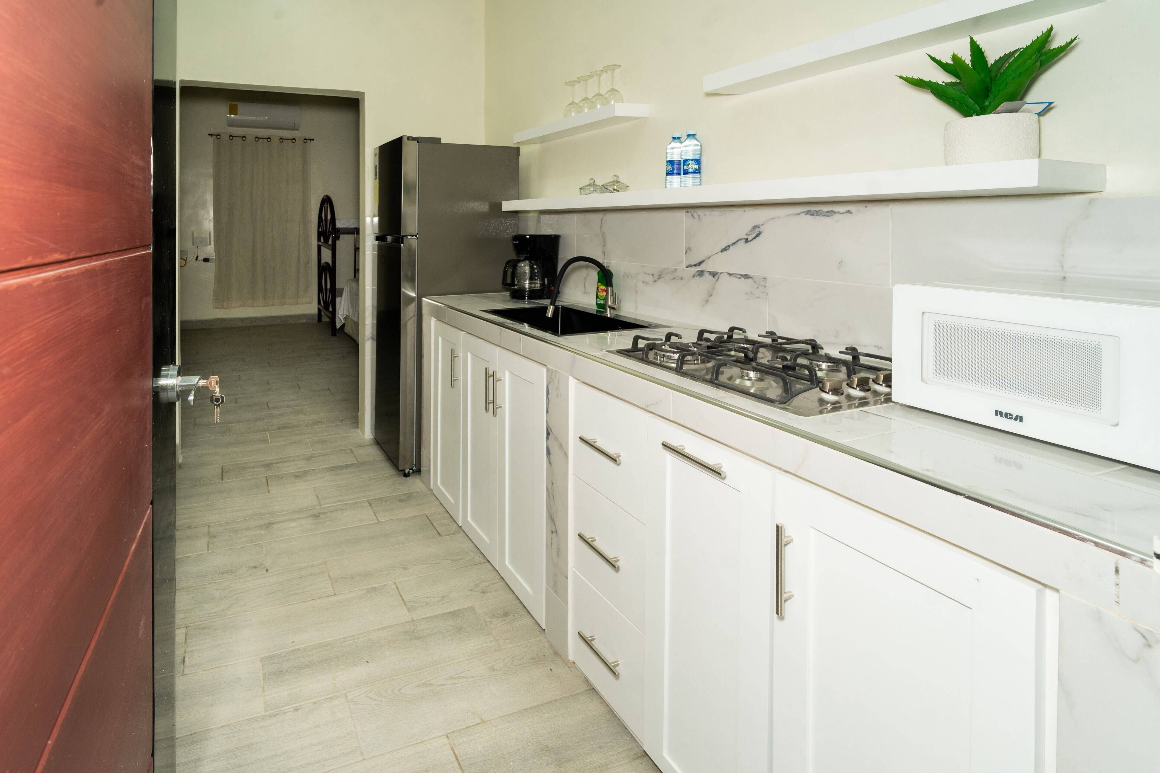 A modern kitchen with white cabinets, a gas stove, a refrigerator, and a microwave.