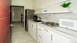 Una cocina moderna con armarios blancos, una estufa a gas, un refrigerador y un microondas.