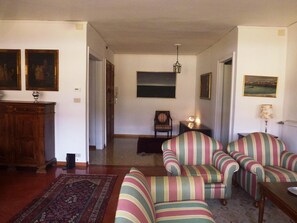 Ein Wohnzimmer mit gestreiften Sesseln, einem Holzschrank und einem Teppich.