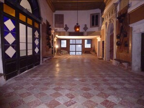 A spacious hallway with a checkered floor, large windows, and a hanging light fixture. - Panoramic view in San Marco overlooking the rooftops (Venezia)